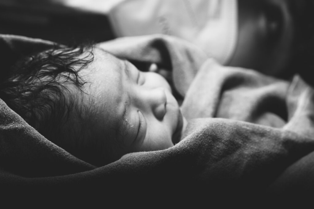 Neugeborenes Baby schläft eingewickelt in eine weiche Decke